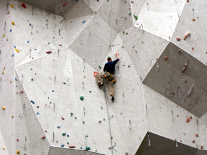 Things to do with friends - a man climbing an indoor rock wall.